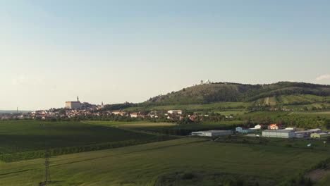 Mikulow-town-below-Svatý-Kopeček-hill-in-Moravia-landscape,-drone-shot