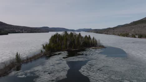 Islet-At-Lake-Tremblant-Covered-With-Ice-Starting-To-Melt-After-Winter-In-Tremblant,-Canada