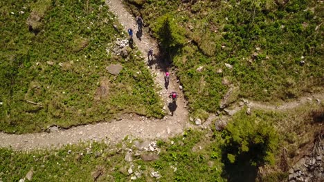 Family-hiking-in-the-swiss-alps-on-a-gravel-path,-top-view-by-drone