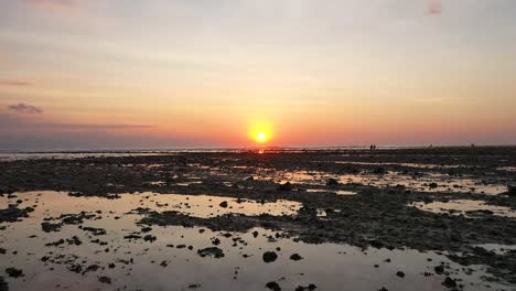 Espectacular-Toma-De-Drones-De-La-Costa-Durante-La-Marea-Baja-Con-El-Sol-Reflejado-En-La-Isla-De-Gili-Trawangan,-Bali,-Indonesia-Y-Puesta-De-Sol-Detrás-Del-Muelle