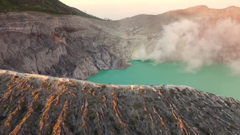 Dramatic-aerial-view-of-a-creator-at-Kawah-Ijen-volcano-with-turquoise-sulfur-lake-at-sunrise