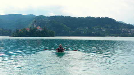Frau,-Die-Ihr-Boot-In-Der-Mitte-Des-Bleder-Sees-In-Richtung-Bleder-Insel-In-Slowenien-Rudert