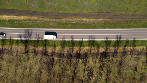 Aerial-shot-of-traffic-on-highway-through-wooded-landscape,-drone-pov
