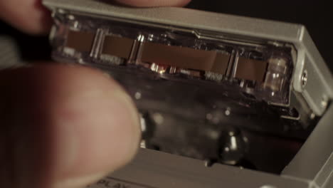 Microcassette-Recorder-Cassette-Being-Inserted-And-Record-Button-Being-Activated-With-Reels-In-Motion-Visible