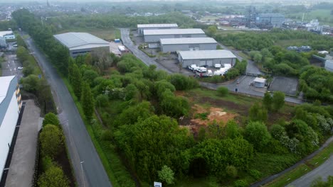 Industrial-processing-warehouse-depot-aerial-view-across-green-space-ecological-park-land