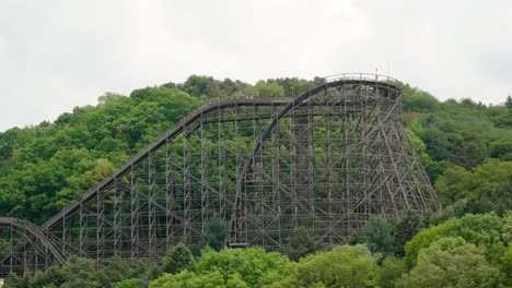 A-roller-coaster-on-a-forested-hill-thrills-screaming-riders-at-an-amusement-park