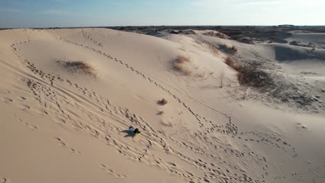 Aerial-View-of-Person-Sledding-Down-Sandy-Hill-of-Dune-in-Desert-Landscape-of-Monahans-Sandhills-State-Park,-Texas-USA,-Drone-Shot