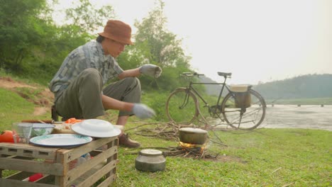 Scenic-view-of-a-male-guy-breaking-sticks-and-putting-in-a-stove-for-cooking-along-the-riverside-in-rural-countryside-in-Loc-Bin,-district-of-Lạng-Sơn-province-in-the-Northeast-region-of-Vietnam