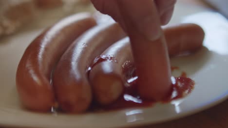 Dipping-a-sausage-in-ketchup.-Close-up-shot
