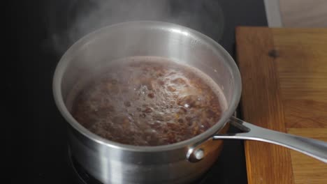 Boiling-buckwheat-crops-in-metal-pot-on-hot-steam-water,-static-view
