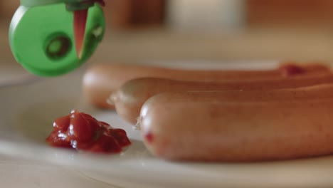 Pouring-ketchup-on-a-plate-with-sausages