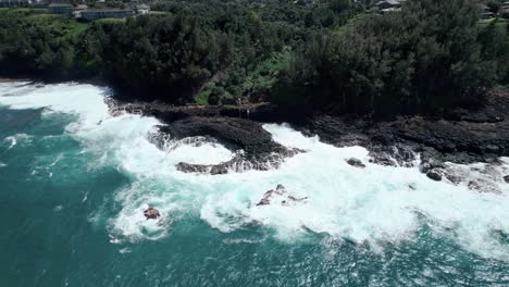 Giant-waves-crash-against-the-rocky-north-shore-of-Kauai,-Queen's-bath,-aerial-orbit