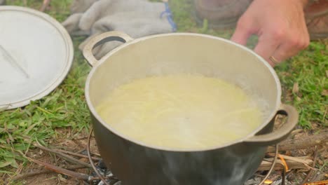 High-angle-shot-of-spaghetti-boiling-in-a-metal-bowl-over-a-stove-with-smoke-coming-out-in-Loc-Binh,-Lạng-Sơn-province,-Vietnam-at-daytime
