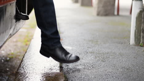 Man-with-dark-shoes-walks-out-from-a-train-at-a-trainstation