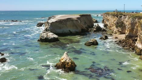 A-picturesque-rocky-shoreline-near-Pismo-Beach-with-gentle-waves---aerial-view-in-slow-motion