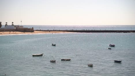 Beautiful-view-out-towards-small-fishing-boats-parked-in-harbor-next-to-sandy-beach