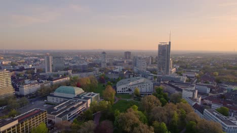 Essen-City-Skyline,-Theater-and-Park-at-dawn,-aerial-pull-back-view,-Ruhr-area-Germany