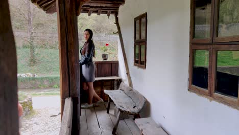 A-beautiful-young-girl-stands-on-the-wooden-balcony-of-an-old-house-and-walks-with-a-smile-on-her-face