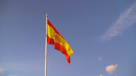 Schöne-Spanische-Flagge,-Die-Gegen-Blauen-Himmel-Mit-Wenigen-Wolken-Weht