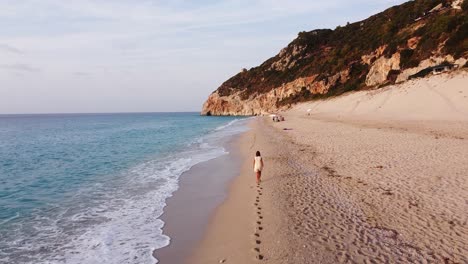 Woman-leaves-Footprints-during-beachwalk-on-Milos-Beach,-Lefkada-Island,-Greece---Aerial-Dolly