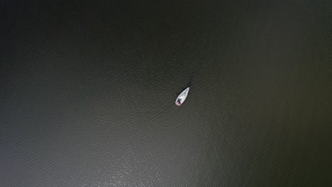 Top-down-view-of-small-sailing-boat-making-a-course-change-in-calm-conditions,-Netherlands