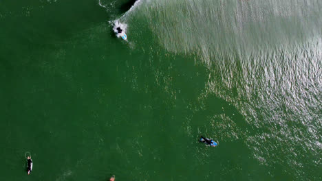 Top-View-Of-Turquoise-Beach-With-Several-Surfers-Enjoying-The-Foamy-Waves-In-San-Francisco,-California-USA