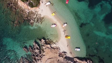 Pedal-Boats-and-Small-White-Sandy-Beach-at-Ksamil-Islands,-Albania---Aerial-Top-Down-Ascending