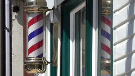 Close-up-of-turning-barber-pole-with-reflection-in-window