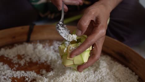 Der-Vorgang,-Reis-Vor-Dem-Kochen-In-Das-Ketupat-Zu-Geben