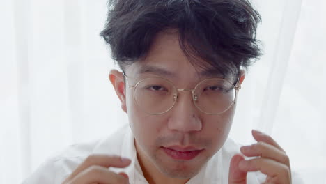 Asiatischer-Mann-Mit-Brille-Und-Gesundem,-Gutem-Haar,-Der-In-Die-Kamera-Schaut-Und-Sich-Verwöhnt,-Indem-Er-Seine-Haare-Aufräumt