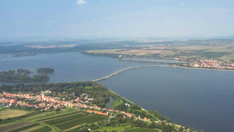 Narrow-causeway-over-Věstonice-reservoir-between-two-villages,-drone