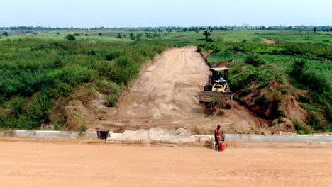 Using-front-loader-heavy-equipment-in-Nigeria-to-clear-vegetation-for-road-construction---sliding-aerial-view