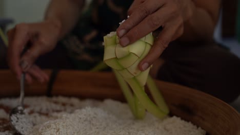 Der-Vorgang,-Reis-Vor-Dem-Kochen-In-Das-Ketupat-Zu-Geben