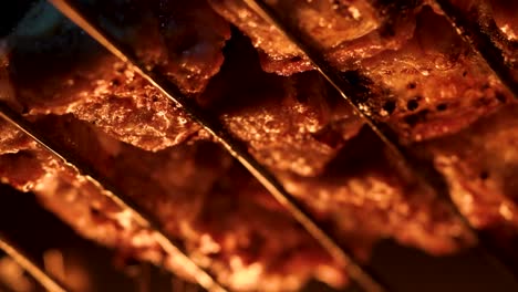 Cooking-pieces-of-meat-at-the-grill-over-intense-fire,-close-up-macro-shot