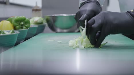 Chef-chopping-a-cabbage-using-a-knife-with-black-gloves-on-a-green-cutting-board
