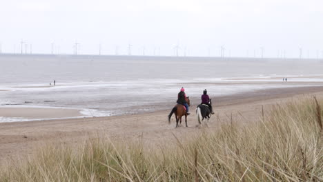 Two-girls-horse-riding-on-a-beach