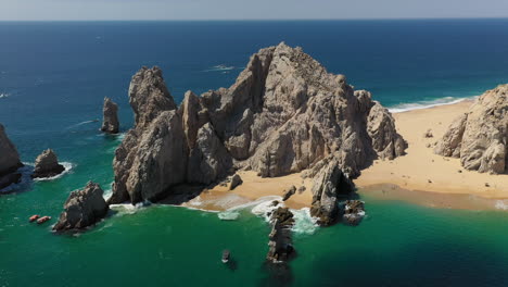 Drone-shot-of-Playa-del-Amor-and-El-Arco-natural-sea-cliffs-in-Cabo-San-Lucas-Mexico,-wide-and-rotating