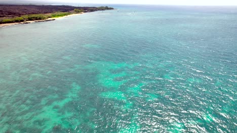 The-calm-turquoise-ocean-waters-of-the-Hawiian-Islands-with-a-view-of-the-beach-and-coastline---aerial-flyover