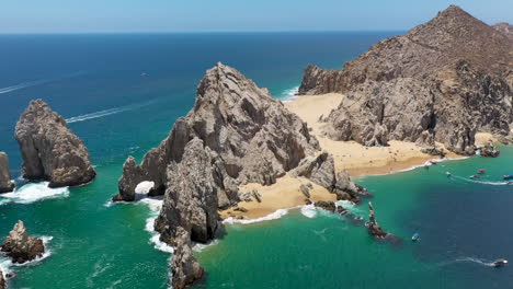 Drone-shot-of-Playa-del-Amor-and-El-Arco,-a-natural-archway-in-the-sea-cliffs,-in-Cabo-San-Lucas-Mexico,-revealing