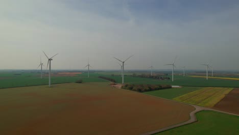Lissett-airfield-wind-turbine-farm-blades-spin-on-agricultural-farmland-aerial-view-rising-over-Yorkshire-countryside