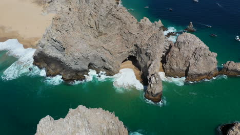 Cinematic-drone-shot-of-waves-crashing-on-sea-cliffs-with-Playa-del-Amor-and-El-Arco-in-view-in-Cabo-San-Lucas-Mexico