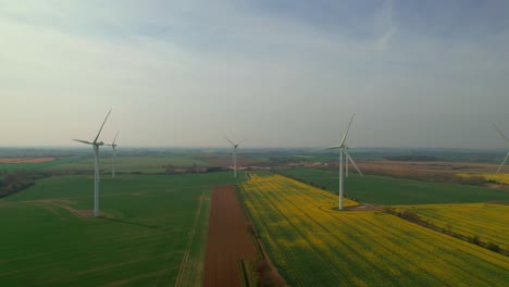 Eolic-wind-turbines-with-blades-rotating-on-colored-fields-of-English-countryside