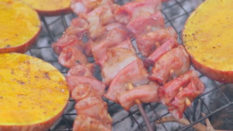 Close-up-of-squid-skewers-and-spicy-pumpkin-pieces-grilling-on-rural-barbecue