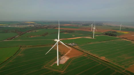 Lissett-airfield-rotating-wind-turbine-farm-on-agricultural-farmland-aerial-rising-view-Yorkshire-countryside