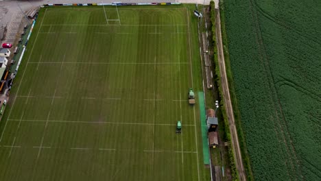 Drohnenaufnahme-Von-Zwei-Traktoren,-Die-Das-Gras-Auf-Dem-Rugbyplatz-Von-Canterbury-Schneiden