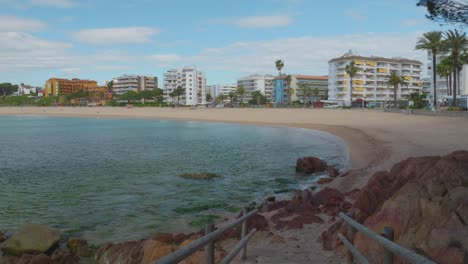 View-of-the-main-beach-of-Lloret-de-Mar-with-the-buildings-in-the-background-and-the-transparent-turquoise-blue-water-of-the-beach-recorded-in-4K-10bit-view-of-Fanals-beach