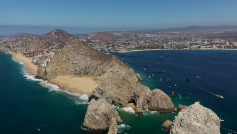 Drone-shot-of-resorts-on-Playa-El-Médano-then-revealing-Playa-del-Amor,-Lover's-Beach,-and-El-Arco,-a-natural-archway-in-the-sea-cliffs-in-Cabo-San-Lucas-Mexico,-wide-and-rotating