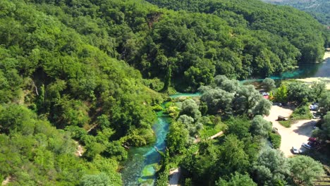 Drone-shot-of-the-Blue-Eye-in-Albania---drone-is-ascending-and-panning-down,-revealing-its-beautiful-colours-and-clear-water