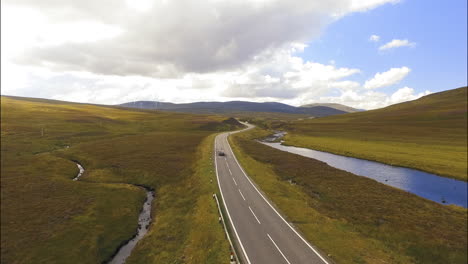 Dark-Car-Travel-on-Highway-in-Scotland,-Aerial-Drone-Follow-Shot