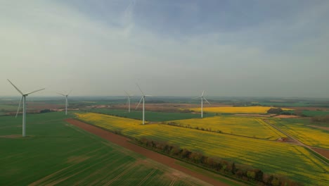 Drone-flying-towards-wind-turbines-for-eolic-energy-production-in-English-countryside,-Yorkshire-in-UK